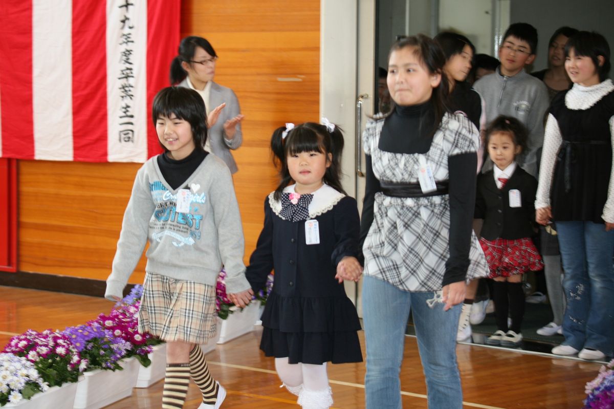 上級生と手をつなぎ式場の体育館に入場する新1年生