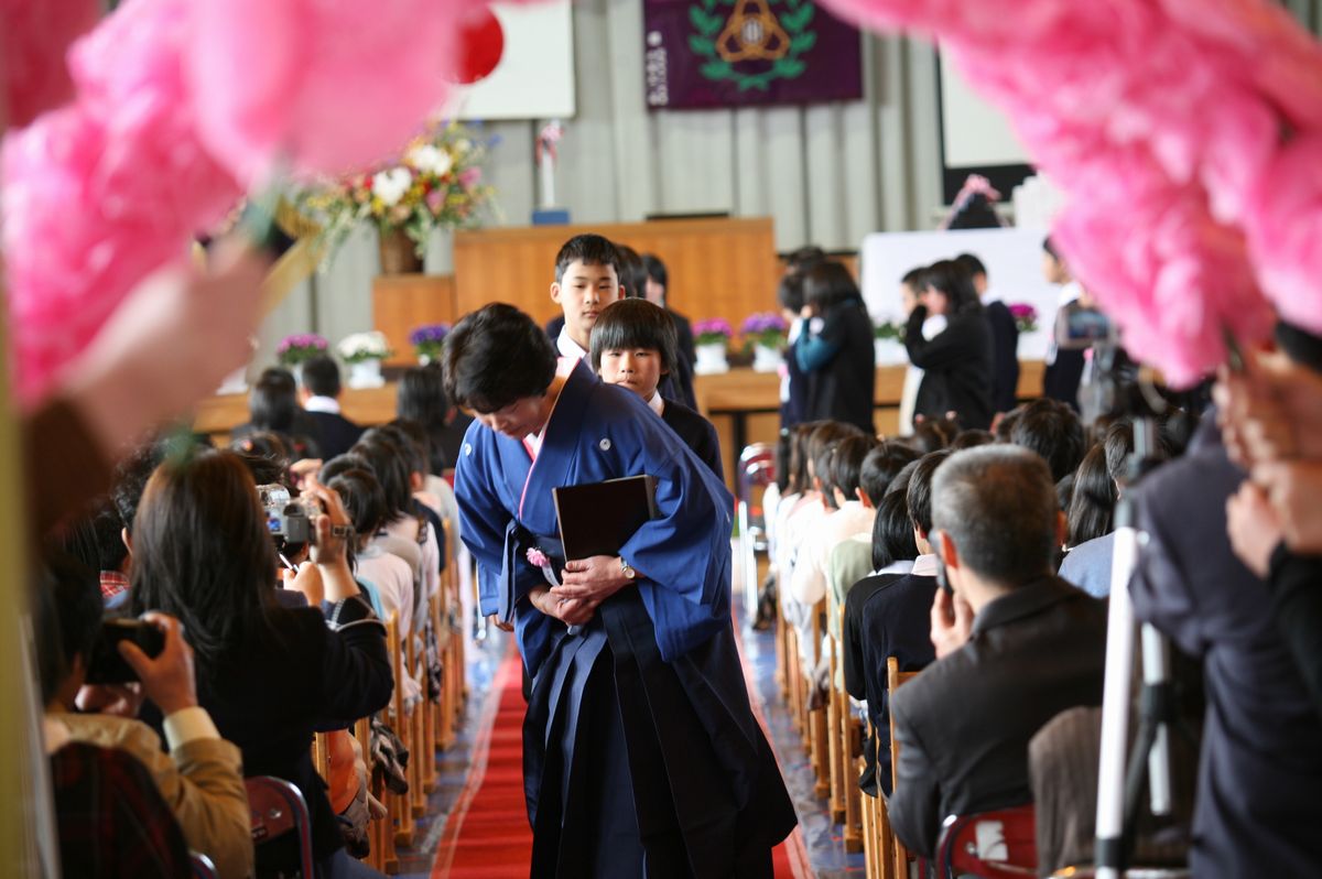 花のアーチをくぐり退場する卒業生と担任の先生