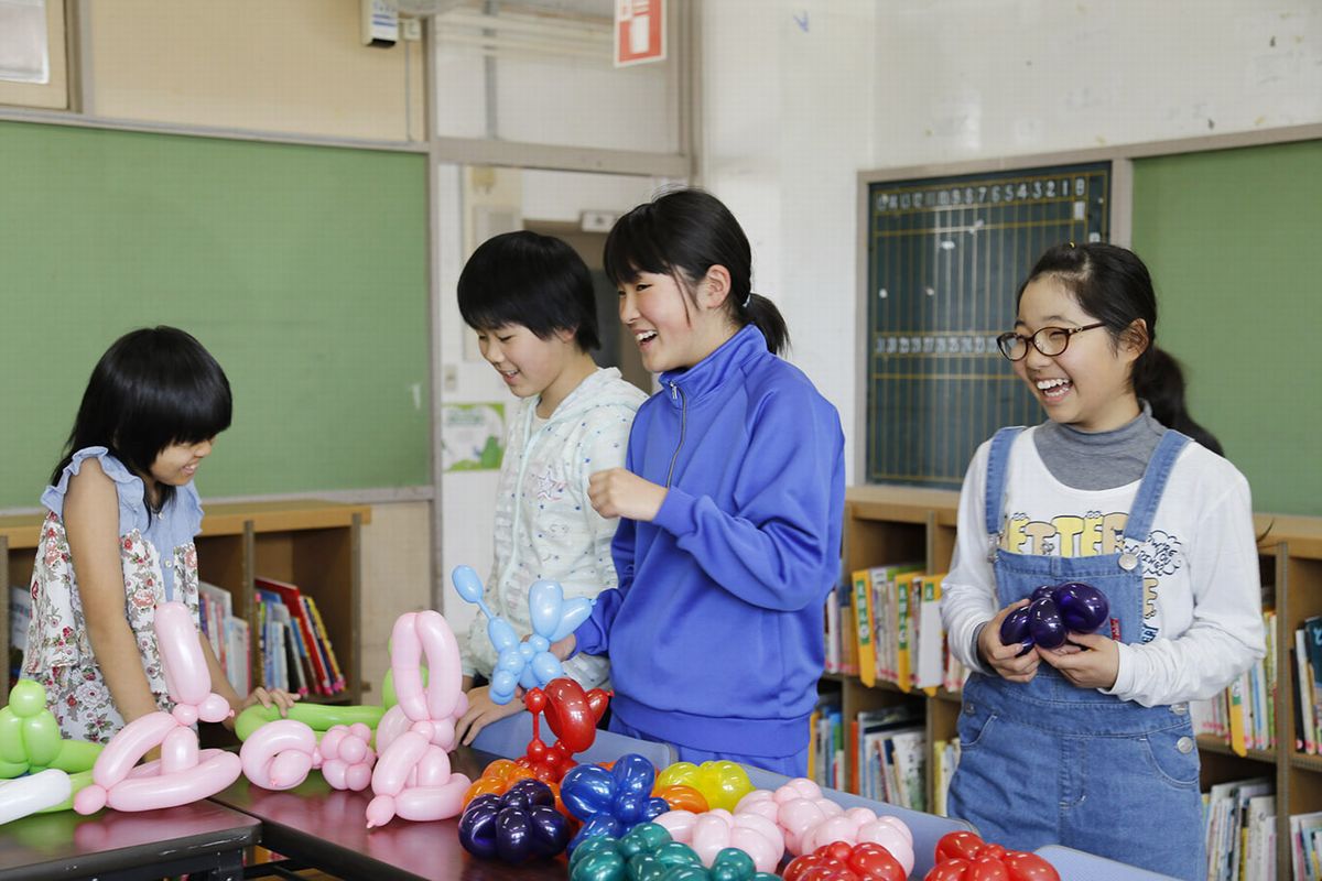 風船おじさんにプレゼントされた風船を選ぶ児童