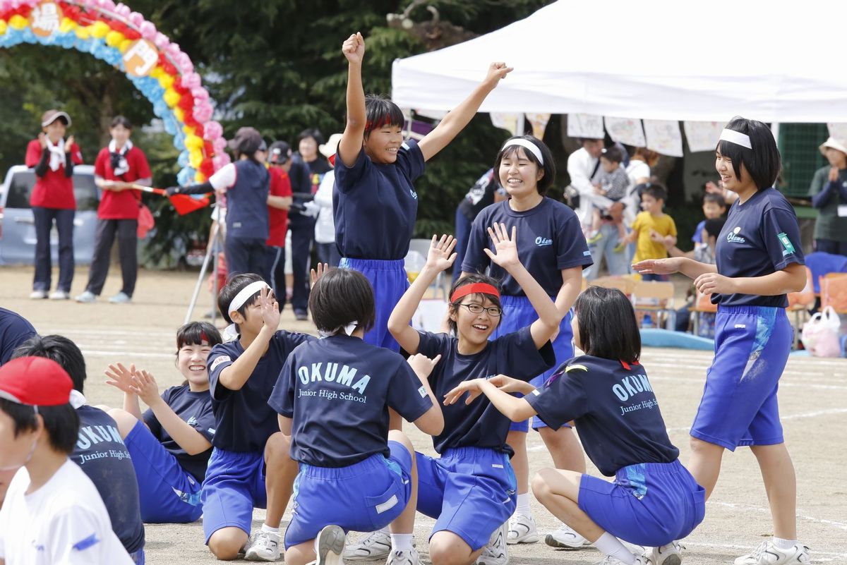 両手を上げてガッツポーズする生徒とハイタッチし合う周りの生徒たち