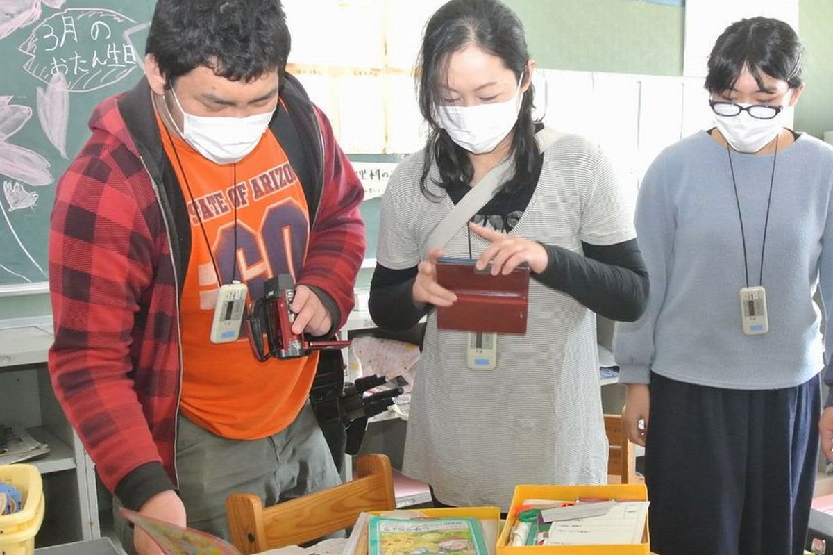 当時、子どもが使っていた学用品を撮影するお母さん