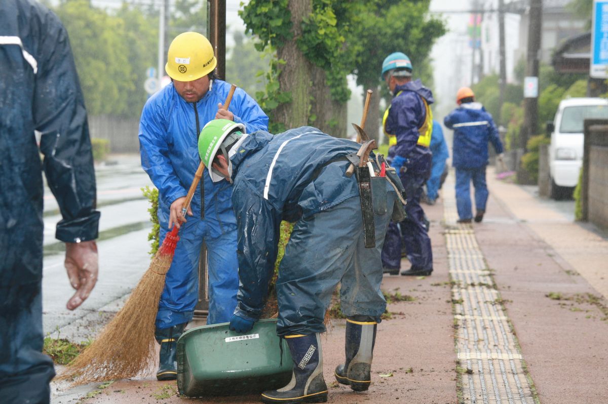 歩道の植え込みの除草作業後、刈った葉や枝を集める参加者