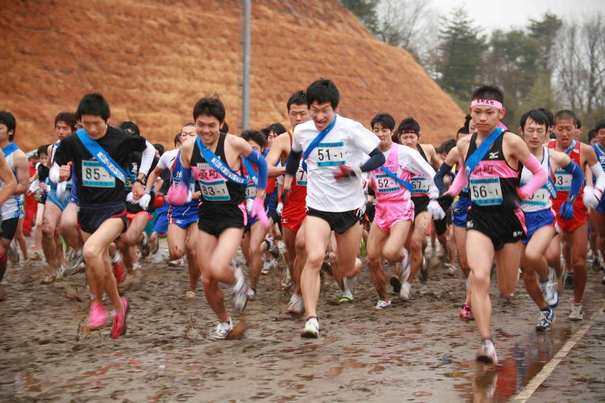 泥しぶきを上げてスタートする一般男子の部参加選手