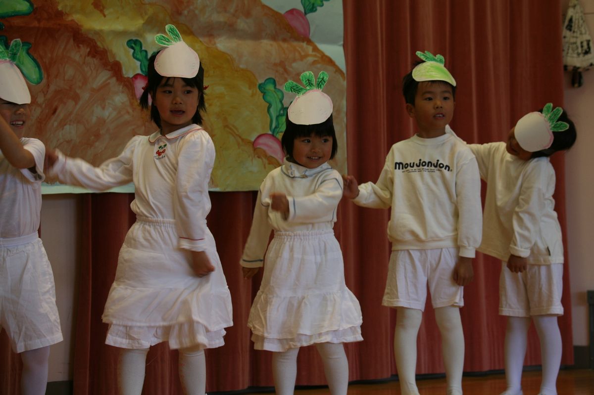 頭にかぶのお面を着けてかわいらいしく踊る園児たち