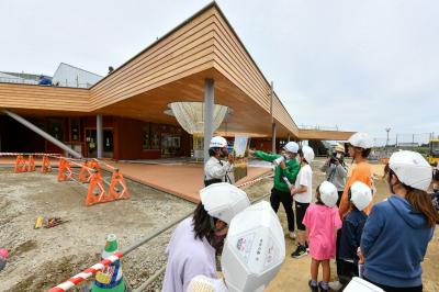 町内大川原地区に整備中の新教育施設で5月25日、学び舎ゆめの森の児童生徒と教職員を対象とした現場見学会が開かれました。児童生徒と教職員ら約40人が参加し、建設が進む校舎や体育館などを巡りました。写真は、幼保ゾーンの外観を見学する子どもたちの様子。