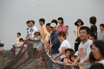 毎年恒例の地引き網で力いっぱい網を引く海水浴客