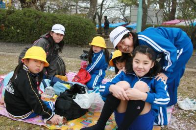 桜のじゅうたんの上でおやつを楽しむ児童たち